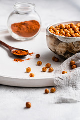 gebackene Kichererbsen mit paprikapulver auf weißem holzteller platziert und von vorne fotografiert