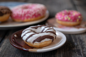 Various donuts on old wooden table. With chocolate fill and nuts, pink glazed and with stars. 