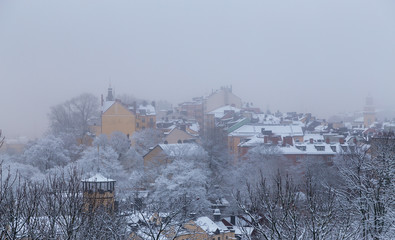 Fototapeta premium Old houses on a hill in Stockholm on a foggy winter day with snow on, Sweden