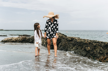 Mother and daughter holding hands and walking on beach. Mom and dauther happy family lifestyle concept