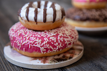 Various donuts on old wooden table. With chocolate fill and nuts, pink glazed and with stars. 