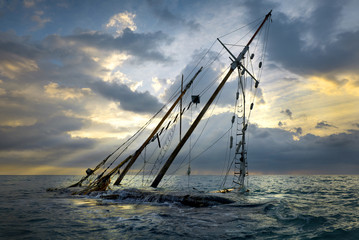 Shipwreck on beach. Boat stranded on the shore. Ship submerged by the waves on sunset.