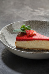 piece of cheesecake with strawberries on a dark background