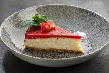 piece of cheesecake with strawberries on a dark background