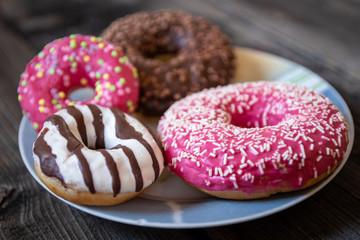 Various donuts on old wooden table. With chocolate fill and nuts, pink glazed and with stars. 