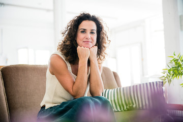 Confident woman sitting on her couch, smiling