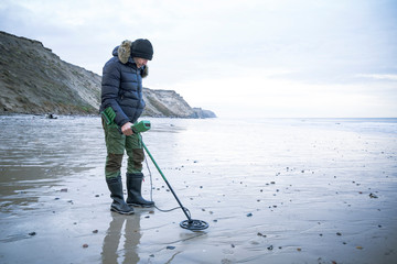 Man with metal detector at the sand beach