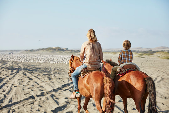 Chile, Vina del Mar, mother with son riding horses on the beach