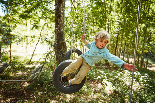 Boy balancing on tires at an adventure park in forest