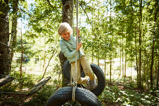 Happy boy balancing on tires at an adventure park in forest