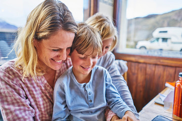 Happy mother with two sons sitting at table in a cafe