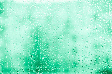 Raindrops on window glass on the magic mint color background