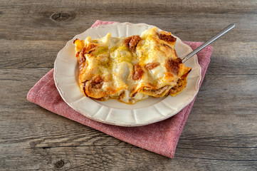 Cannelloni, Italian pasta pastry tubes stuffed with mince meat with white bechamel sauce and cheese crust, in the plate on the old wooden background.