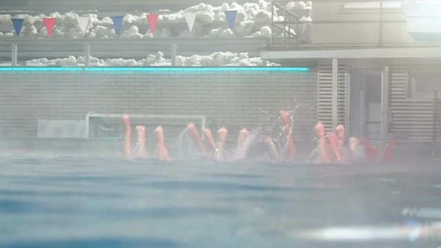Synchronized swimming. Slender legs girls athletes stick out of the water in open pool in winter. Young girls learn swimming in the pool. Young girls are trained to competitive swimming in the pool