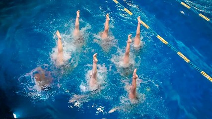 Synchronized swimming. Young girls learn swimming in the pool. Young girls are trained to competitive swimming in the pool. Water team sports, girls synchronized swimming