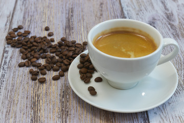 A Cup of fragrant black coffee and a handful of coffee beans on an old wooden table close-up. in the morning to drink. horizontal view.