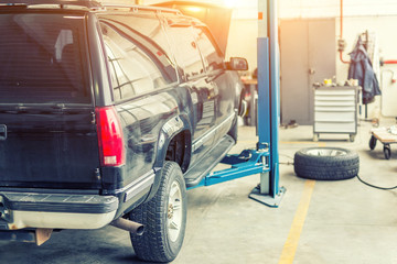 Car service center. Old rusty offroad SUV vehicle raised on lift at maintenance station. Automobile...