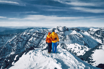 Naklejka na ściany i meble Couple standing at the top of the snow covered mountain Jebel Toubkal, Atlas Morocco