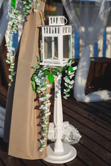 Fototapeta na wymiar High white candlestick decorated with flowers