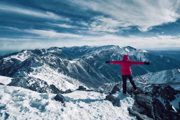 Happy alpinist girl standing at snow covered top of the peak of Jebel Toubkal in Atlas mountains Morocco - obrazy, fototapety, plakaty