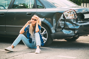 girl sits on the road, near the broken car and calls on the phone, calling for help.