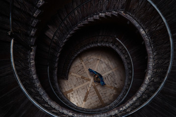 Young woman standing in center of an spiral staircase, top view