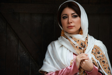 Young azeri woman in traditional Azerbaijani dress standing at the wooden door