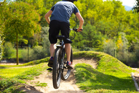 Man is jumping over a hill in a bike parcours with his mountainbike