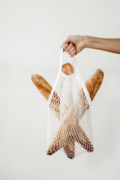 woman holding a tote bag with baguettes