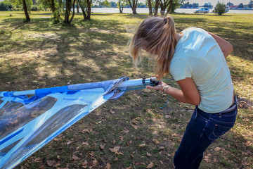 Blonde long haired young attractive girl downhauling the sail for windsurfing session on Nove...