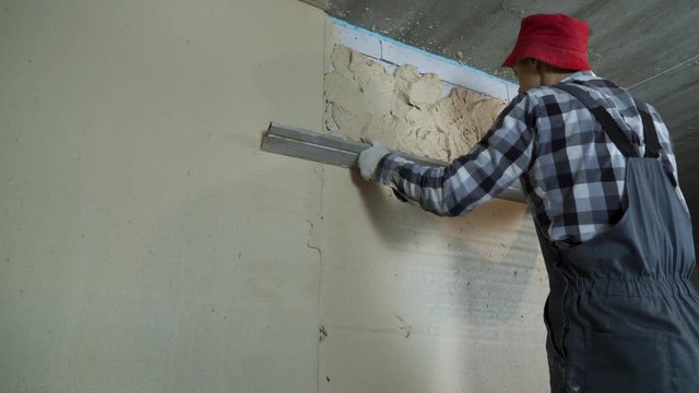 builder leveling plaster on aerated concrete block wall with construction ruler