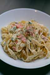 Homemade tagliatelle with salmon and dill on a black wooden table