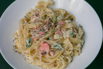 Homemade tagliatelle with salmon and dill on a black wooden table