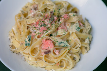 Homemade tagliatelle with salmon and dill on a black wooden table