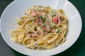 Homemade tagliatelle with salmon and dill on a black wooden table