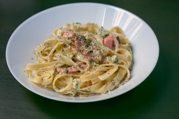 Homemade tagliatelle with salmon and dill on a black wooden table