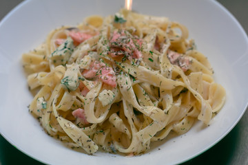 Homemade tagliatelle with salmon and dill on a black wooden table