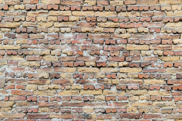 Surface of the old brick wall of red and yellow bricks, bonded with cement mortar.