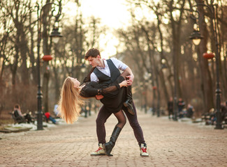 Elegant young couple in love in classic style passionately dancing in city park