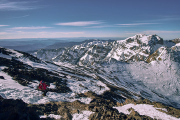 Backpacker tourist girl descending from the peak of Jebel Toubkal mountain covered by snow in High...