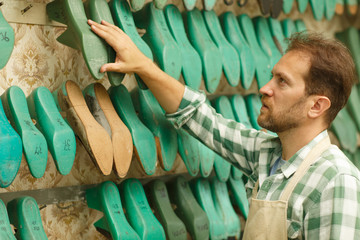 Male sewing master standing next to shelves with plastic pads.