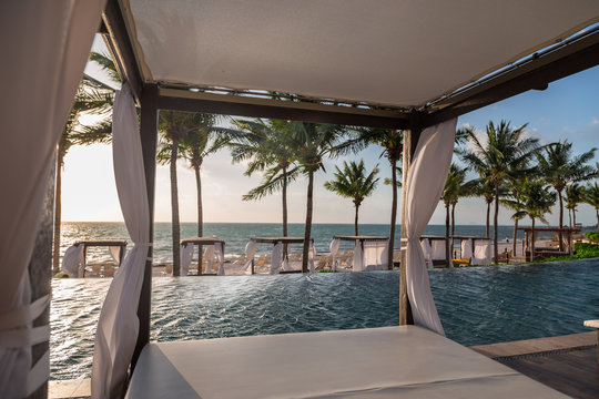 Private beds in a lounge area of a a high end Mexican resort overlooking the ocean at sunrise.