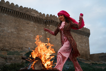 Traditional Azerbaijani Novruz holiday celebration with beautiful girl Jumping over the fire,