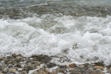 Fototapeta na wymiar Close to a pebble beach against the backdrop of sea waves
