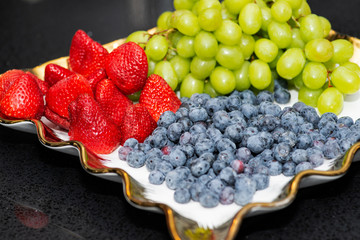 Fresh fruit platter with arranged organic blueberries, strawberries, grapes on banquet table at business or wedding event venue.