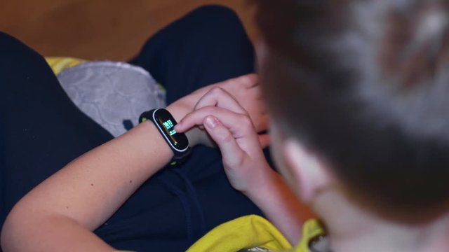 The boy scrolls menu in smart watch