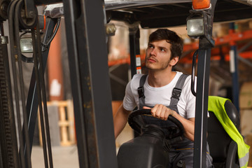 Concentrated forklift loader operator sitting and driving machine. Handsome man in special uniform...