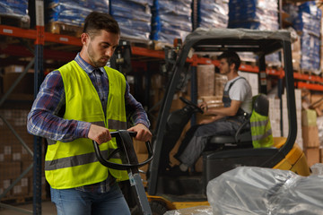 Two workers of warehouse concentrated on their work with goods. Handsome loader in reflective...