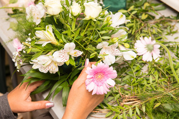 Florist female making a bouquet of different flowers at working table
