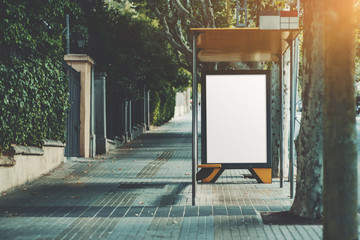 An urban bus stop with blank poster mock-up inside; an informational banner template inside of a...